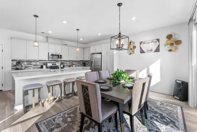 a kitchen with stainless steel appliances kitchen island granite countertop a dining table chairs stove refrigerator and cabinets