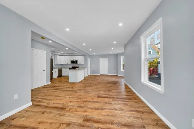 a view of a kitchen with kitchen island a window wooden floor and stainless steel appliances