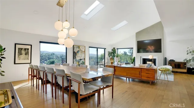 a kitchen with stainless steel appliances granite countertop a stove a refrigerator a sink a dining table and chairs with wooden floor