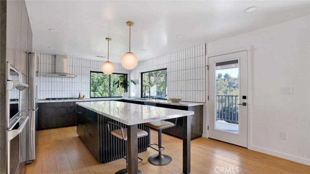 1574 East Dexter Street Covina, CA 91724 - Photo 19 of 56 a kitchen with stainless steel appliances granite countertop a stove a refrigerator a sink a dining table and chairs with wooden floor