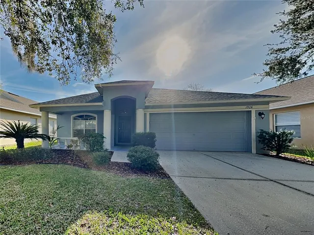 front view of a house with potted plants and a yard