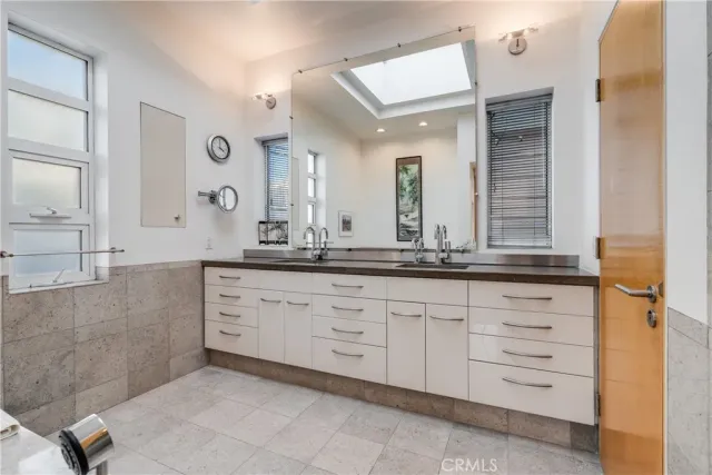a bathroom with a tub 2 sink and a mirror