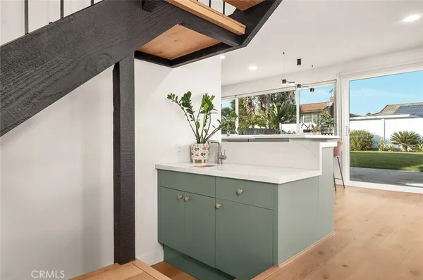 a kitchen with stainless steel appliances kitchen island granite countertop a refrigerator a stove a sink a dining table and chairs with wooden floor