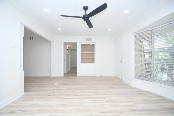 a view of empty room with wooden floor and fan