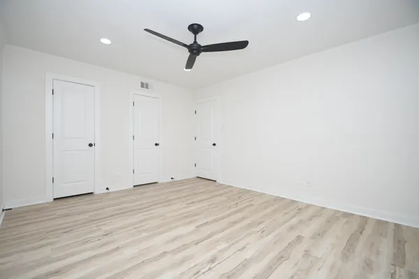 a view of empty room with wooden floor and fan