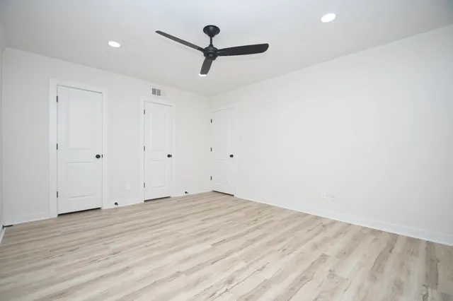 a view of empty room with wooden floor and fan