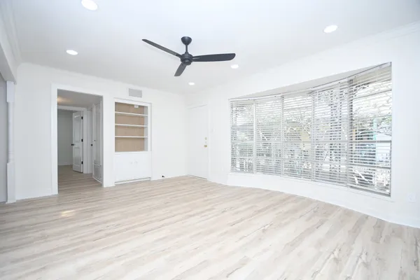 a view of an empty room with a window and a kitchen
