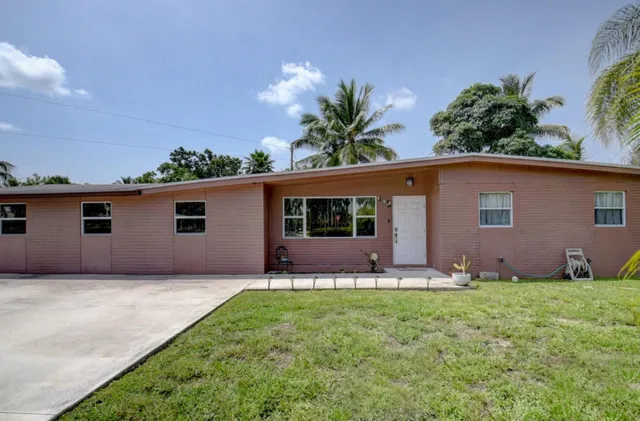 front view of house with a yard and potted plants