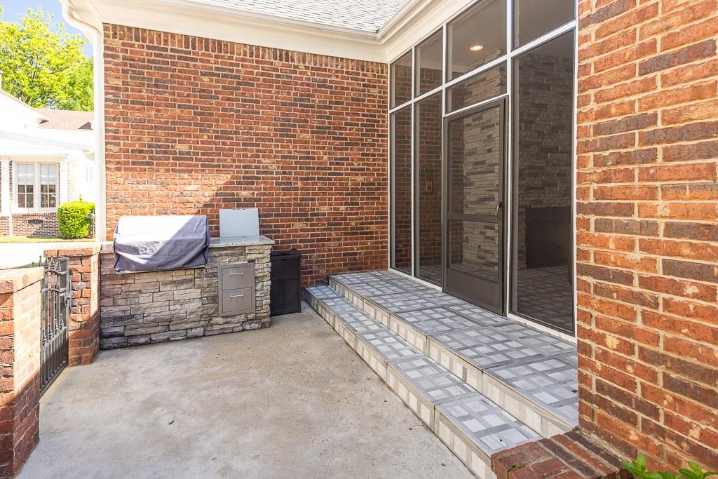 328 Washington Street Collierville, TN 38017 - Photo 30 of 33 Expansive concrete patio with a built-in outdoor kitchen featuring stone veneer, a light-toned countertop, and stainless steel drawers