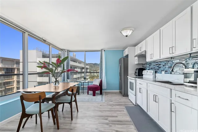 a kitchen with stainless steel appliances kitchen island granite countertop a dining table chairs and a refrigerator