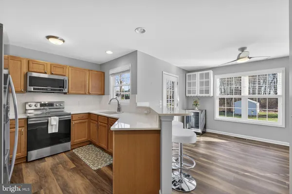 a kitchen with granite countertop a stove top oven a sink dishwasher a dining table and chairs with wooden floor
