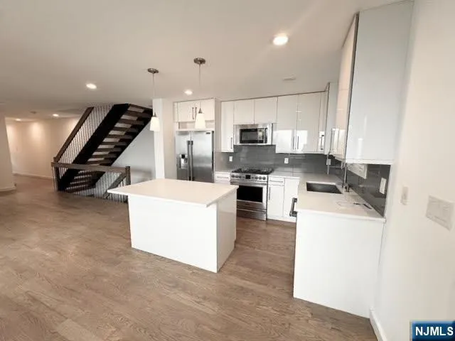 a kitchen with stainless steel appliances a stove a refrigerator a sink and white cabinets