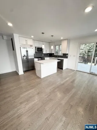 a kitchen with stainless steel appliances a refrigerator a sink a stove top oven a dining table and chairs