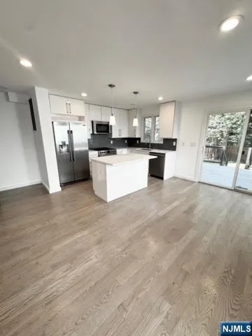 a kitchen with stainless steel appliances a refrigerator a sink a stove top oven a dining table and chairs