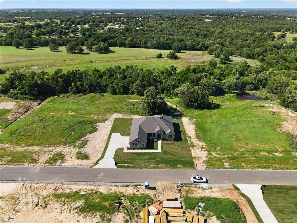 409 Mcalpine Springtown, TX 76082 - Photo 35 of 38 Modern home featuring a light gray exterior with stone accents, a dark shingle roof, and a concrete driveway