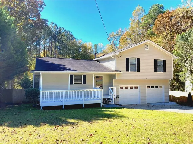 a view of a house with a big yard and large tree