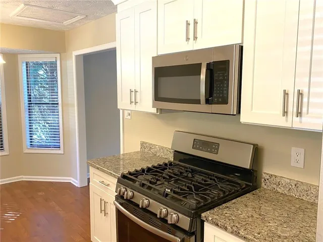 a kitchen with stainless steel appliances granite countertop a stove a sink and a microwave