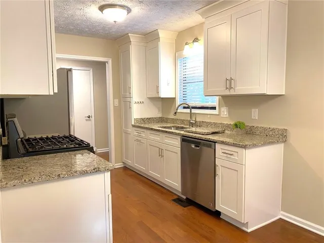an empty room with wooden floor fireplace and windows
