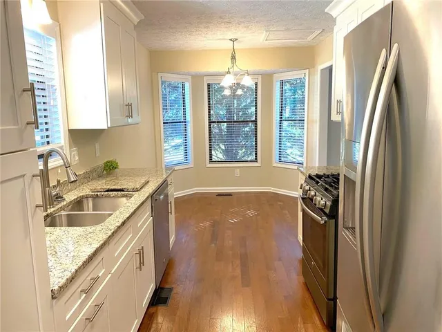 a kitchen with granite countertop white cabinets and white appliances