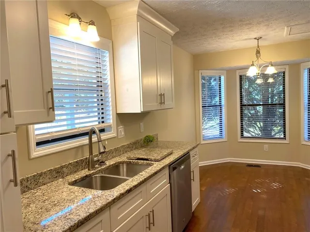 a kitchen with a sink a stove top oven a refrigerator and white cabinets