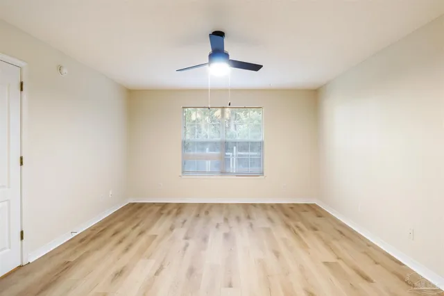 an empty room with wooden floor ceiling fan and windows