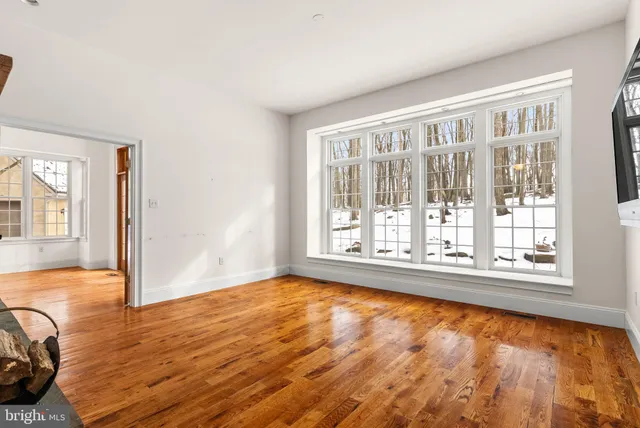 a view of an empty room with window and wooden floor