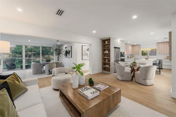 a living room with furniture kitchen view and large windows