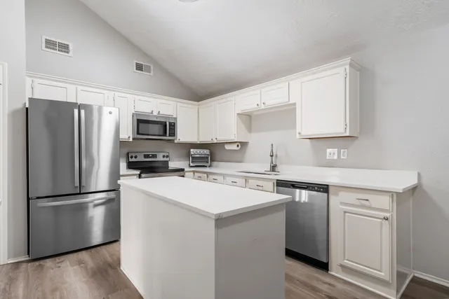 a kitchen with a refrigerator a sink cabinets and wooden floor