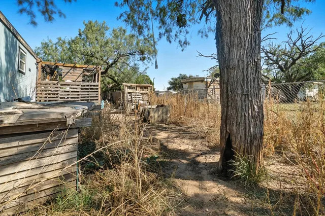 a view of a house with wooden fence and large trees