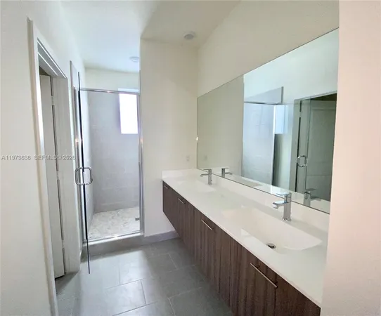 a bathroom with a double vanity sink mirror and shower