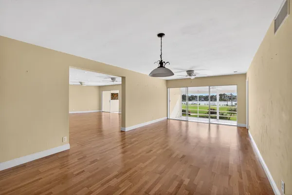 a view of an empty room with a window and wooden floor