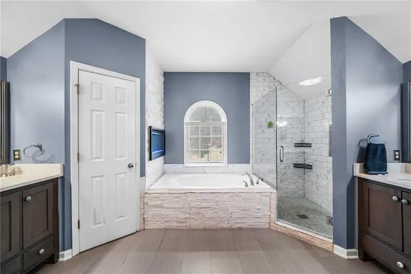 a bathroom with a tub a double vanity sink and mirror