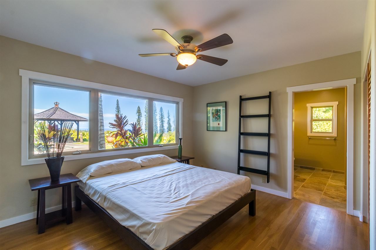 195 Mauu Place Haiku, HI 96708 - Photo 21 of 30 a bedroom with a bed and a large window with wooden floor