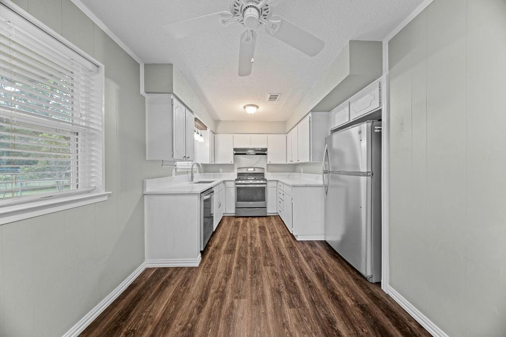 1041 Barber Street Hurst, TX 76053 - Photo 12 of 36 a kitchen with wooden floor a refrigerator and window