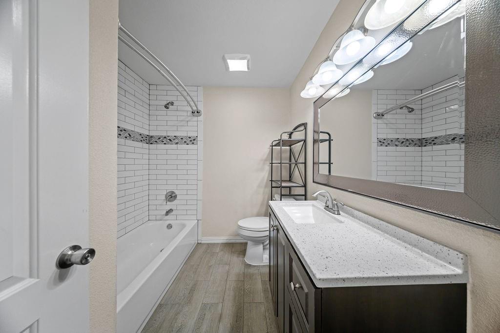 1041 Barber Street Hurst, TX 76053 - Photo 25 of 36 a bathroom with a granite countertop sink a toilet and bathtub