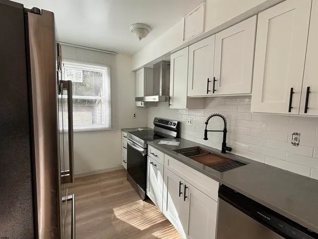 a kitchen with stainless steel appliances granite countertop a sink a stove and a refrigerator