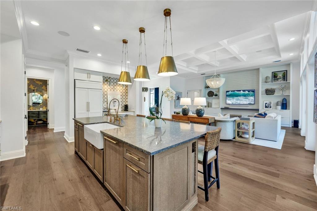 445 Putter Point Drive Naples, FL 34103 - Photo 11 of 44 a kitchen with stainless steel appliances granite countertop center island wooden floor and a view of living room