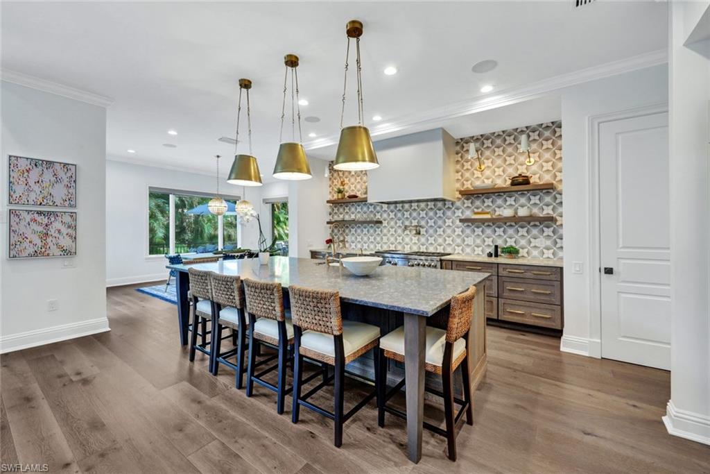445 Putter Point Drive Naples, FL 34103 - Photo 7 of 44 a kitchen with stainless steel appliances kitchen island wooden floors and white cabinets