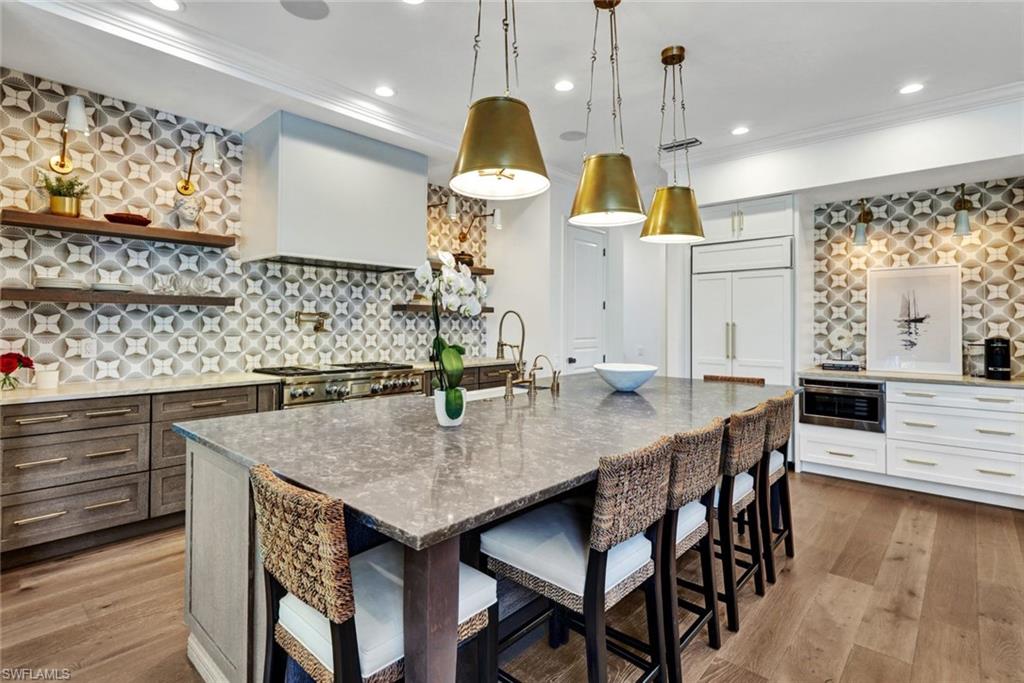 445 Putter Point Drive Naples, FL 34103 - Photo 9 of 44 a kitchen with stainless steel appliances a dining table chairs and wooden floor