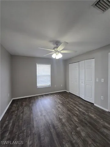 a view of empty room with wooden floor and fan