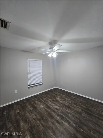 an empty room with a ceiling fan and window