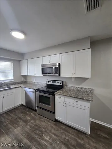 a kitchen with granite countertop white cabinets and white appliances
