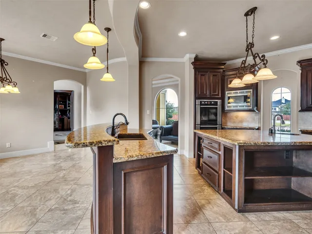 a kitchen with a stove a chandelier and living room view