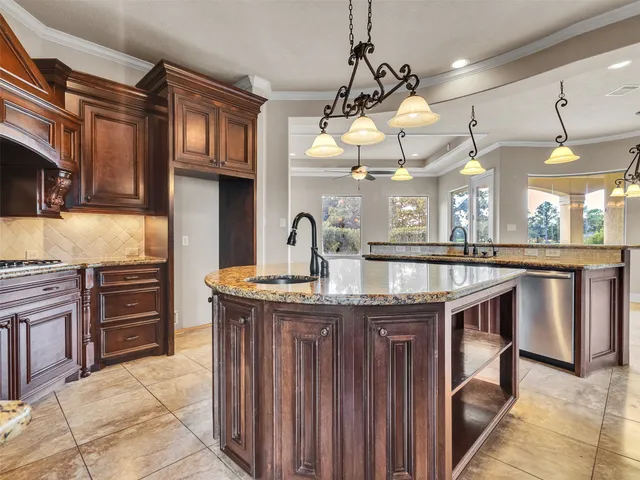 a kitchen with stainless steel appliances granite countertop a sink a stove and a wooden cabinets