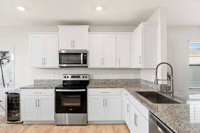 a kitchen with granite countertop white cabinets and stainless steel appliances