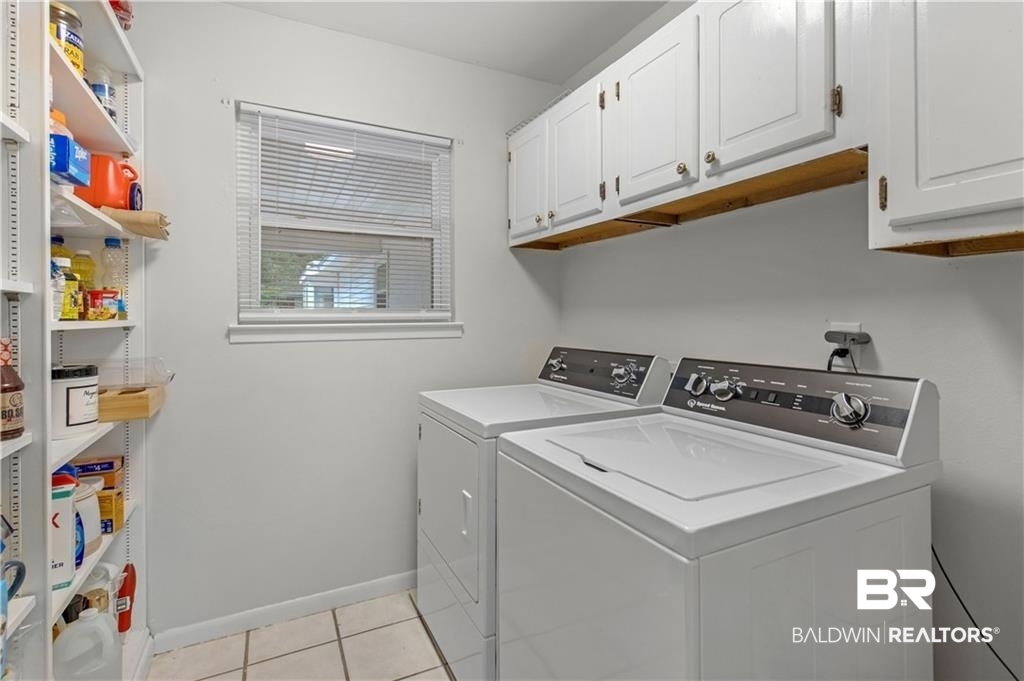 1624 Apex Drive Mobile, AL 36693 - Photo 16 of 29 Clothes washing area featuring washing machine and clothes dryer, light tile patterned floors, and cabinets