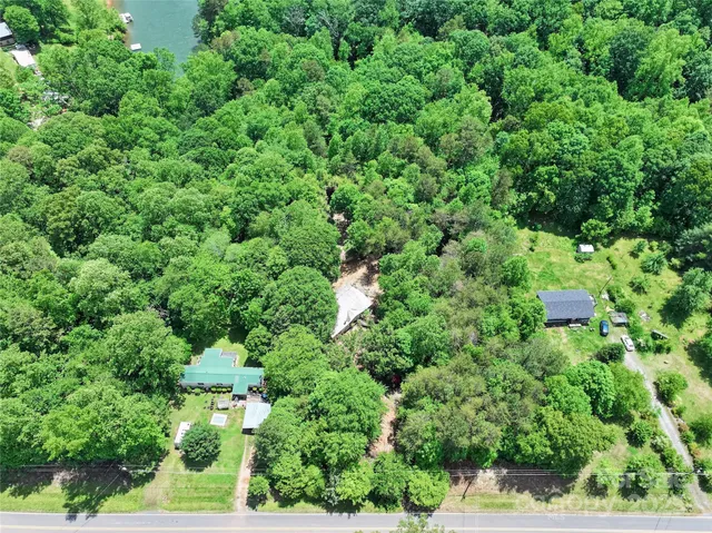 an aerial view of residential house with outdoor space and trees all around