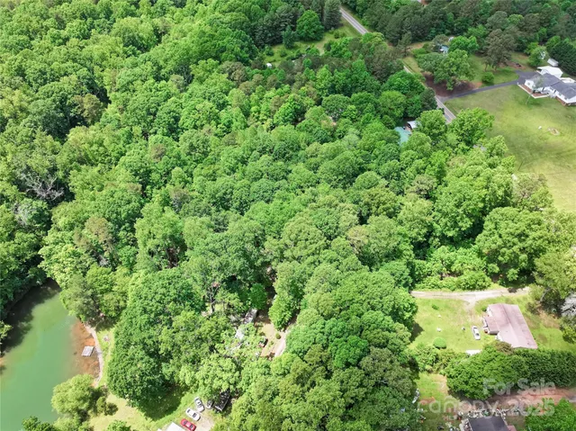 an aerial view of residential house with outdoor space and trees all around