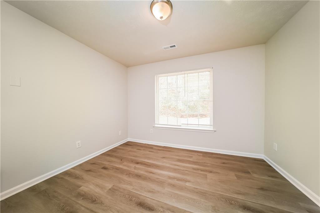 11171 Knotty Pine Place Hampton, GA 30228 - Photo 18 of 26 an empty room with wooden floor and windows