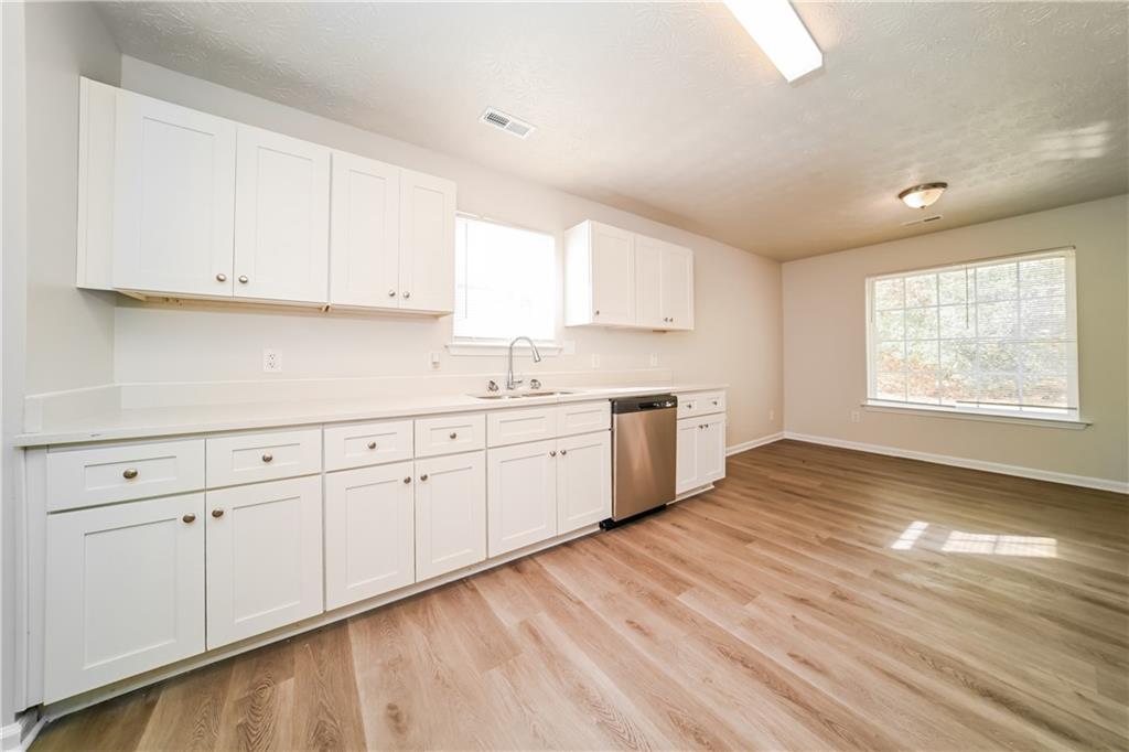 11171 Knotty Pine Place Hampton, GA 30228 - Photo 6 of 26 a large white kitchen with granite countertop a stove a sink white cabinets and wooden floor next to a window